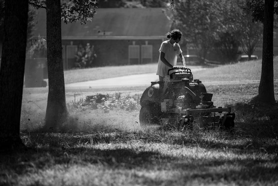 Landscaper pushing a lawn mower across thick green grass